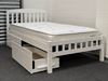 Miki King Single Bed in white, crafted from solid rubberwood, featuring a slatted headboard and footboard with built-in storage drawers for practical organization. The main bed is fitted with a comfortable mattress